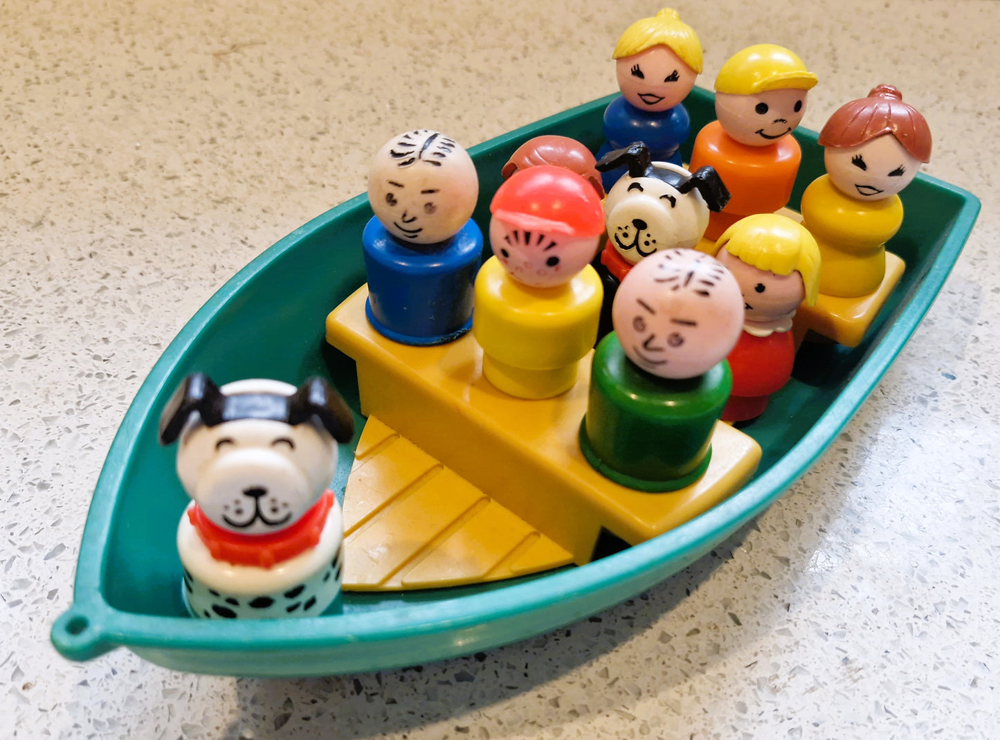 Toy figures of people and a dog on a boat with a textured surface background