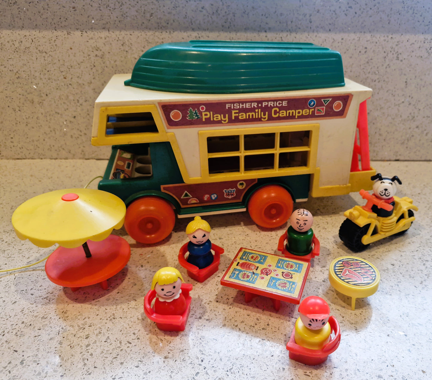 Fisher-Price Play Family Camper toy set with figures and accessories on a textured surface.